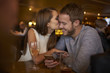 © Guerilla - Young woman kissing man while sitting in bar