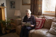 © Guerilla - Senior Woman Sitting On Sofa Reading Book At Home