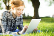 © antgor - Young woman lying on grass in park and using digital tablet