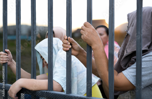 Cuadros en Lienzo Refugee peoples hand holding metal bar on refugee camp site sit