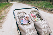 Funny Twins Baby In Double Stroller In Forest