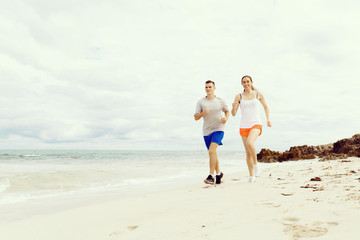 Runners. Young couple running on beach