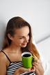 © puhhha - Drink Morning Coffee. Closeup Beautiful Happy Smiling Woman Enjoying Cup Of Coffee In Morning. Model Drinking Hot Beverage. Girl Lying In Bed, Relaxing At Home. Diet Drinks Concept. Healthy Lifestyle