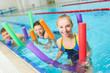 © dreamsnavigator - Happy and smiling group of children learning to swim with pool noodle