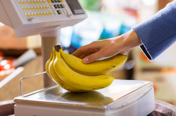 close up of woman hand with banana scales at shop