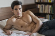 © theartofphoto - Shirtless sexy male model lying alone on his bed