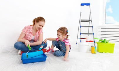 happy family mother and child daughter making repairs, paint wal