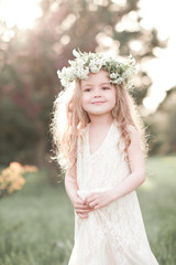 Poster - Smiling baby girl 3-4 year old wearing flower wreath outdoors. Little princess. Childhood.