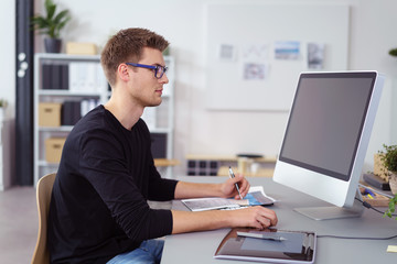 mann arbeitet im büro am bildschirm