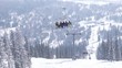 Chair ski lift with skiers against cedar trees forest. Sheregesh ski resort.