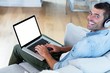 © WavebreakMediaMicro - Portrait of young man listening to music while using laptop
