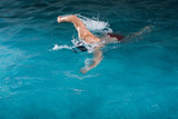 Fototapeta Łazienka - Young man swimming the front crawl in a pool