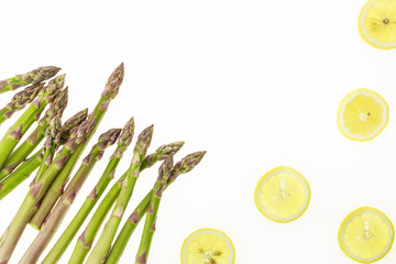 Wall Mural - Bunch of asparagus spears and lemon slices, on white background with copy-space