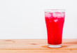 red drinks with soda and ice in glass on wooden background