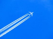Airplane With Chemtrails On Blue Sky
