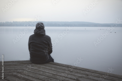 Fotografie, Obraz Einsamer Mann sitzt auf Steg am See oder Fluss / Lonesome Huy u jezera