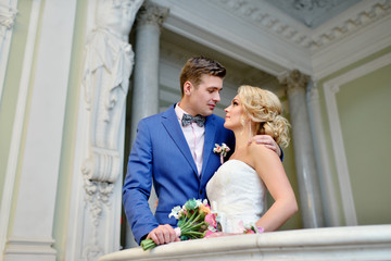 Wall Mural - Wedding couple indoors is hugging each other. Beautiful model girl in white dress. Man in suit. Beauty bride with groom. Female and male portrait. Woman with lace veil. Cute lady and handsome guy