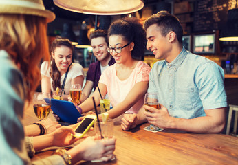 Wall Mural - happy friends with tablet pc and drinks at bar