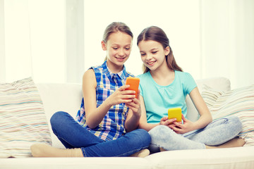 Poster - happy girls with smartphones sitting on sofa