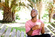 © mimagephotos - Handsome young african man relaxing outdoors with a cup of coffee