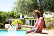 © mimagephotos - Smiling black man sitting by pool