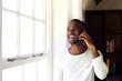 © mimagephotos - Young african man at home making a phone call