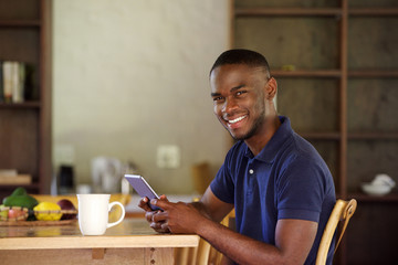 Wall Mural - Young black guy sitting at home with a digital tablet