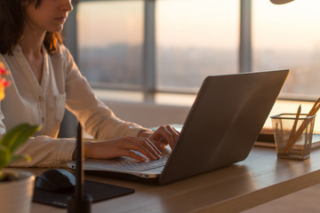side view photo of a female programmer using laptop, working, typing, surfing the internet at workpl