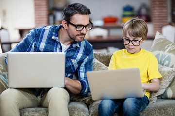 Wall Mural - Father and son using laptop in living room