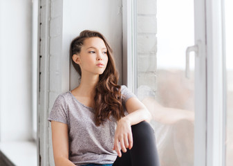 Poster - sad pretty teenage girl sitting on windowsill