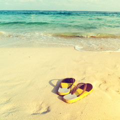 retro slippers on tropical beach in summer - vintage color tone effect