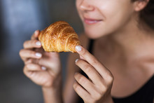 Young Woman Enjoying Breakfast And Holding Croissant In Hand. Mo