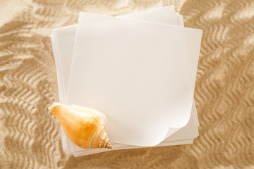 Wall Mural - Blank white paper and seashell in sand