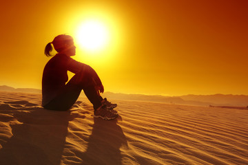 sportswoman resting on top of a sand dune