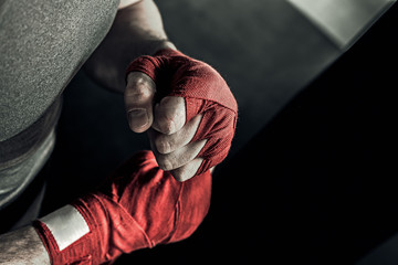 closeup male hand of boxer with red boxing bandages. fists of fighter before the fight or training i