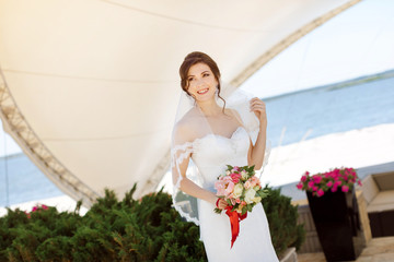 Gorgeous sexy bride in white dress posing on street