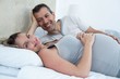 © WavebreakMediaMicro - Expecting couple lying on bed and chatting
