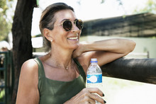 Portrait Of Mature Woman Wearing Sunglasses And Holding Bottle Of Water