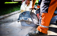Construction Worker Cutting Asphalt Paving For Sidewalk