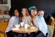 © Nejron Photo - Cheerful multiracial friends taking selfie in a cafe