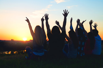 Group of people jumping outdoors; sunset 