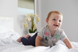 © Monkey Business - A happy baby girl crawling on a bed, copy space on left