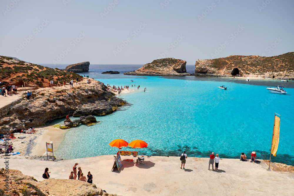 BLUE LAGOON, COMINO, MALTA - APRIL 13, 2016. People enjoy blue lagoon  with crystal clear blue water. - obrazy, fototapety, plakaty 