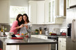 © Monkey Business - Female gay couple embracing make a toast in the kitchen