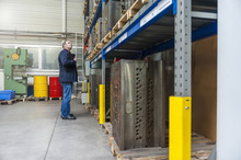 Man Examining Machine Block In Storehouse
