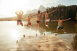 Leinwandbild Motiv Young friends jumping into lake from a jetty