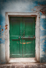 Old Wooden Locked Green Door With Peeling Paint In Blue Wall