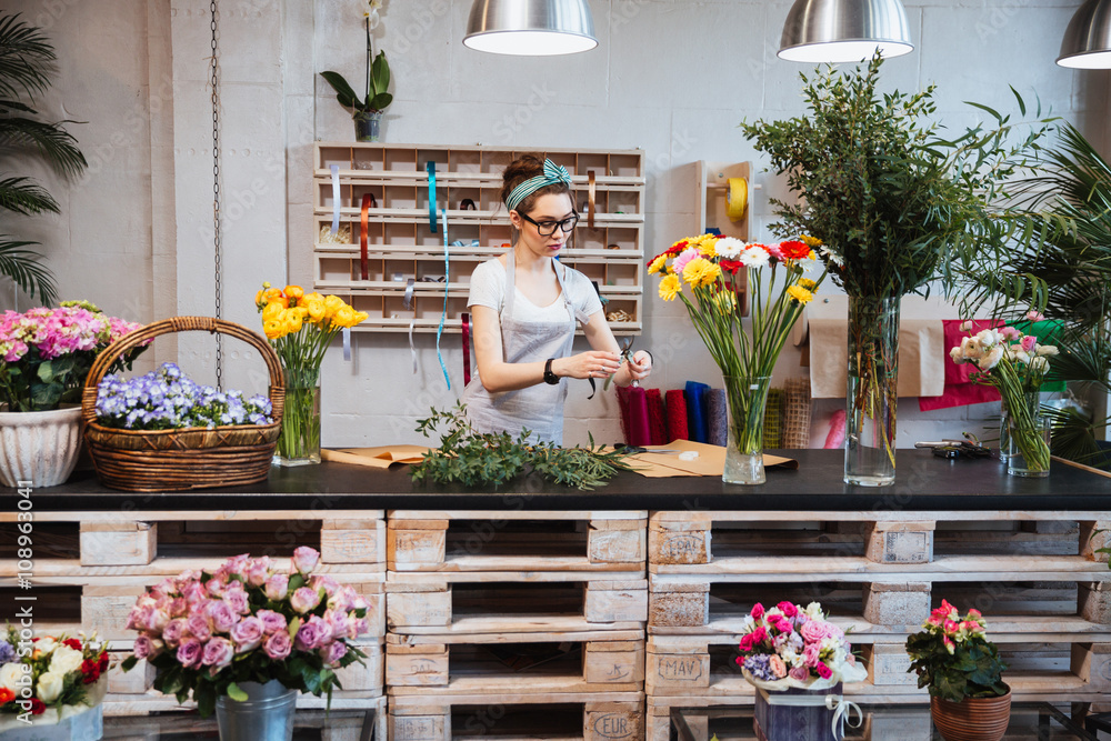 Cute concentrated female florist working in flower shop - obrazy, fototapety, plakaty 