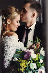 Canvas Print - Romantic happy couple, bride & groom posing near window closeup