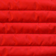 Red quilted textiles with insulation texture. Vertical stripes.  Close up fragment of the top view.